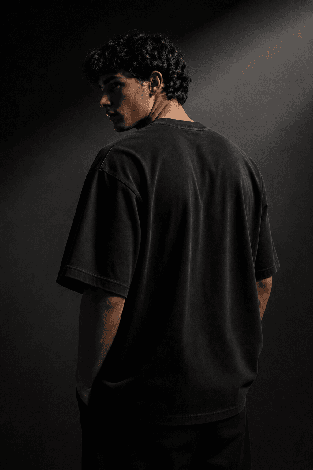 Model wearing an oversized black t-shirt in a dark studio