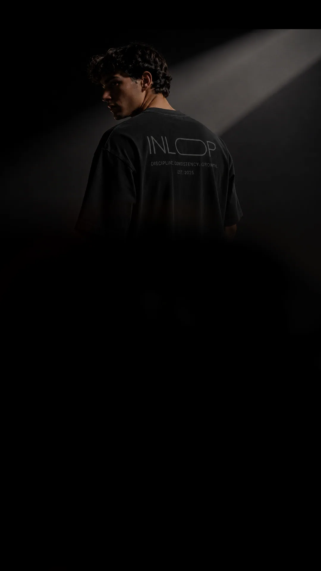 Model wearing black INLOOP streetwear under cinematic studio light
